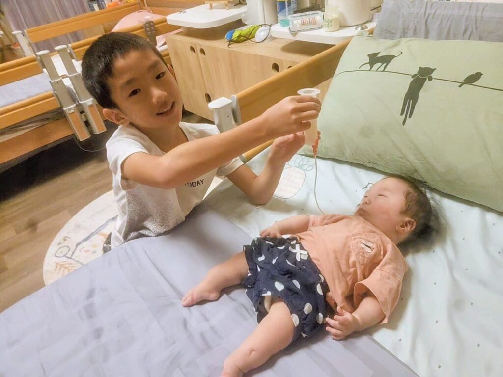 Baby Eva's older brother helping with her feeding | Rare Disorders Society (Singapore) [RDSS]